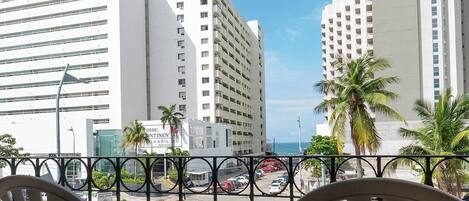 A balcony with two chairs, overlooking a street with cars and buildings.