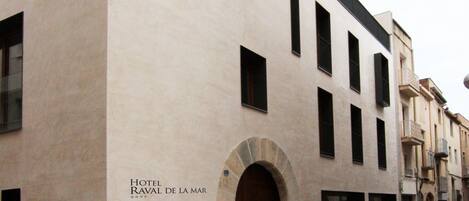 Un edificio con fachada moderna, una amplia entrada en arco y un letrero que indica que es un hotel.