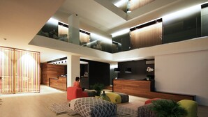 A spacious, modern interior with a high ceiling, a seating area with colorful cushions, and a wooden reception desk. - Hotel Raval de la Mar (Vila-Seca)