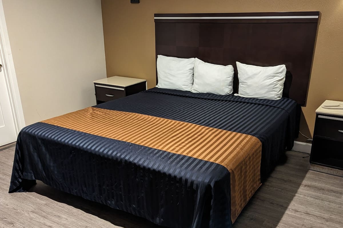 Une chambre d’hôtel avec un grand lit, deux tables de chevet, une petite table et une lampe fixée au mur.