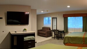 A hotel room with a bed, a desk with a chair, a television, and a window with curtains. - Epic Hotel (Pico Rivera)