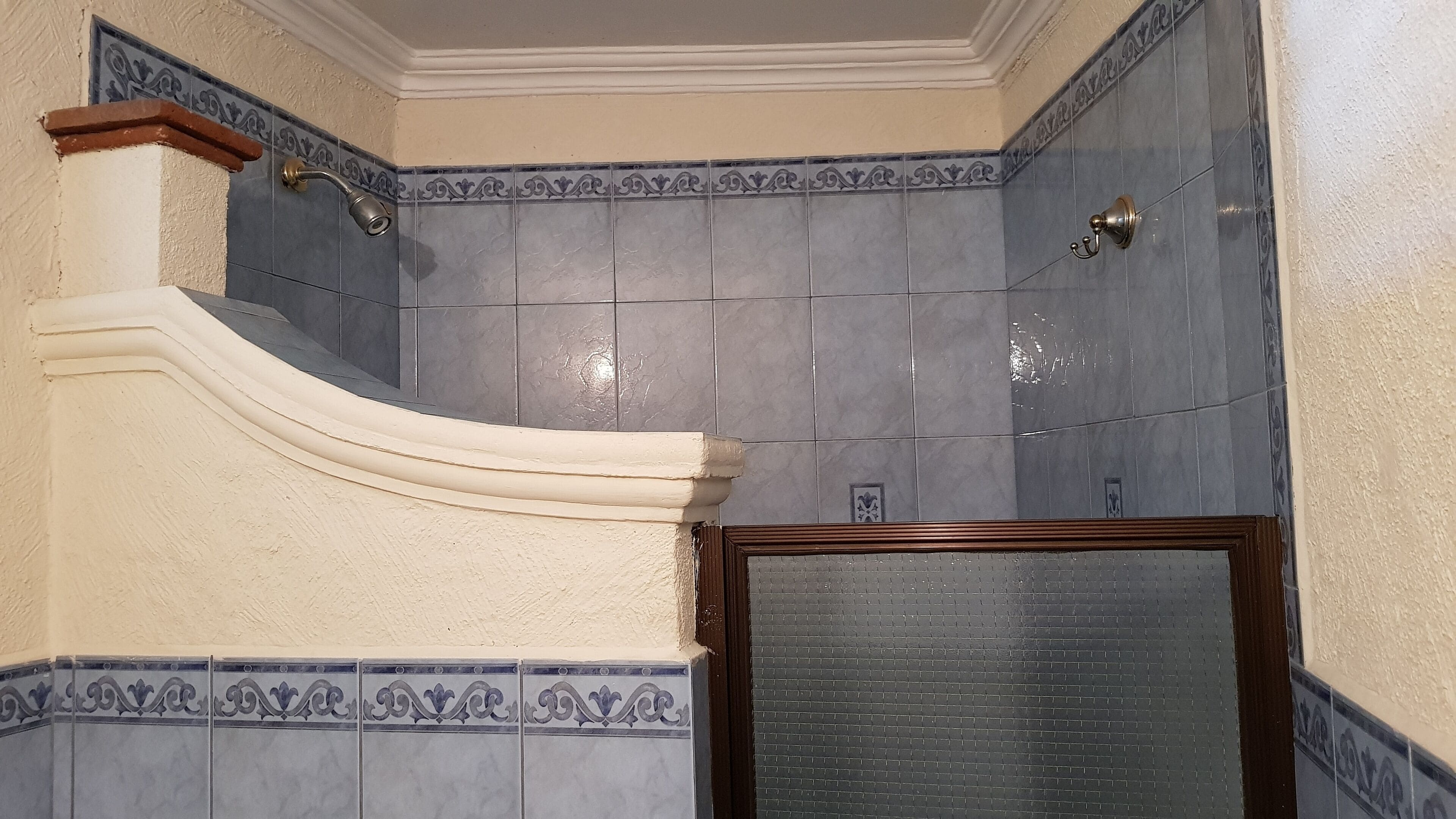 Un bagno con piastrelle grigie, zona doccia e una porta con cornice decorativa.