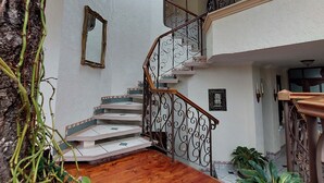 A multi-level interior with a wooden staircase, a stained glass window, and potted plants. - Aurora Express (Guatemala City)