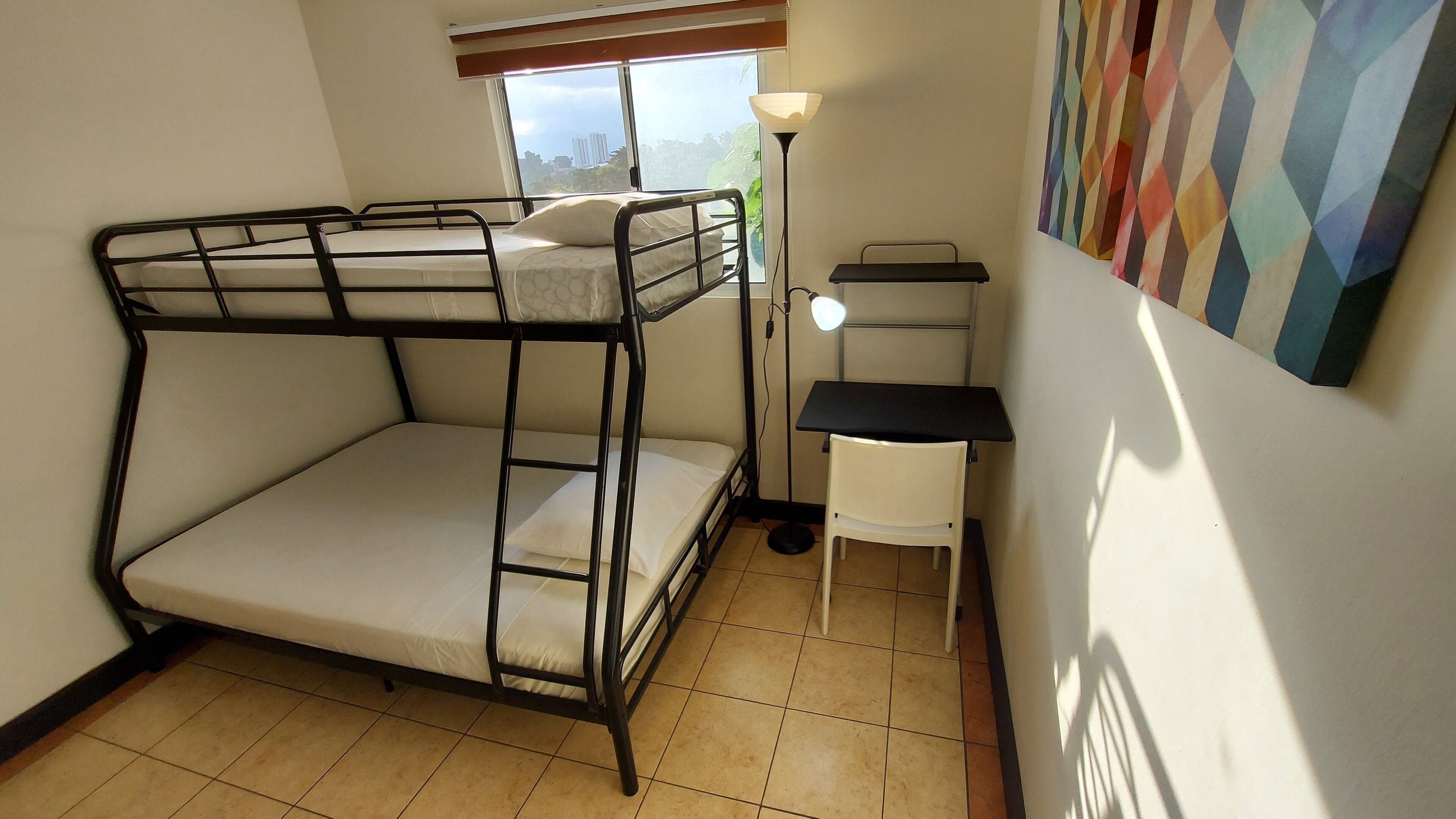 Habitación con literas, un escritorio y una silla, con ventana.