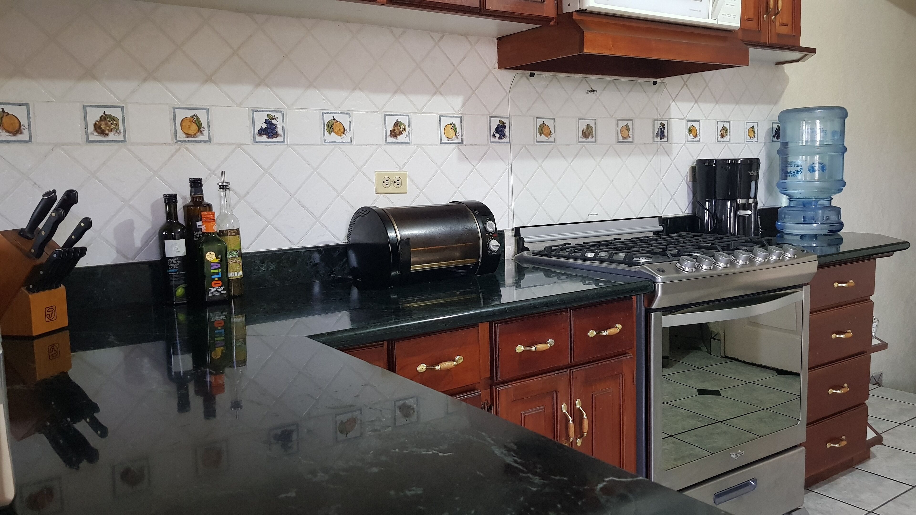 A kitchen with a stove, toaster, water dispenser, and various bottles.
