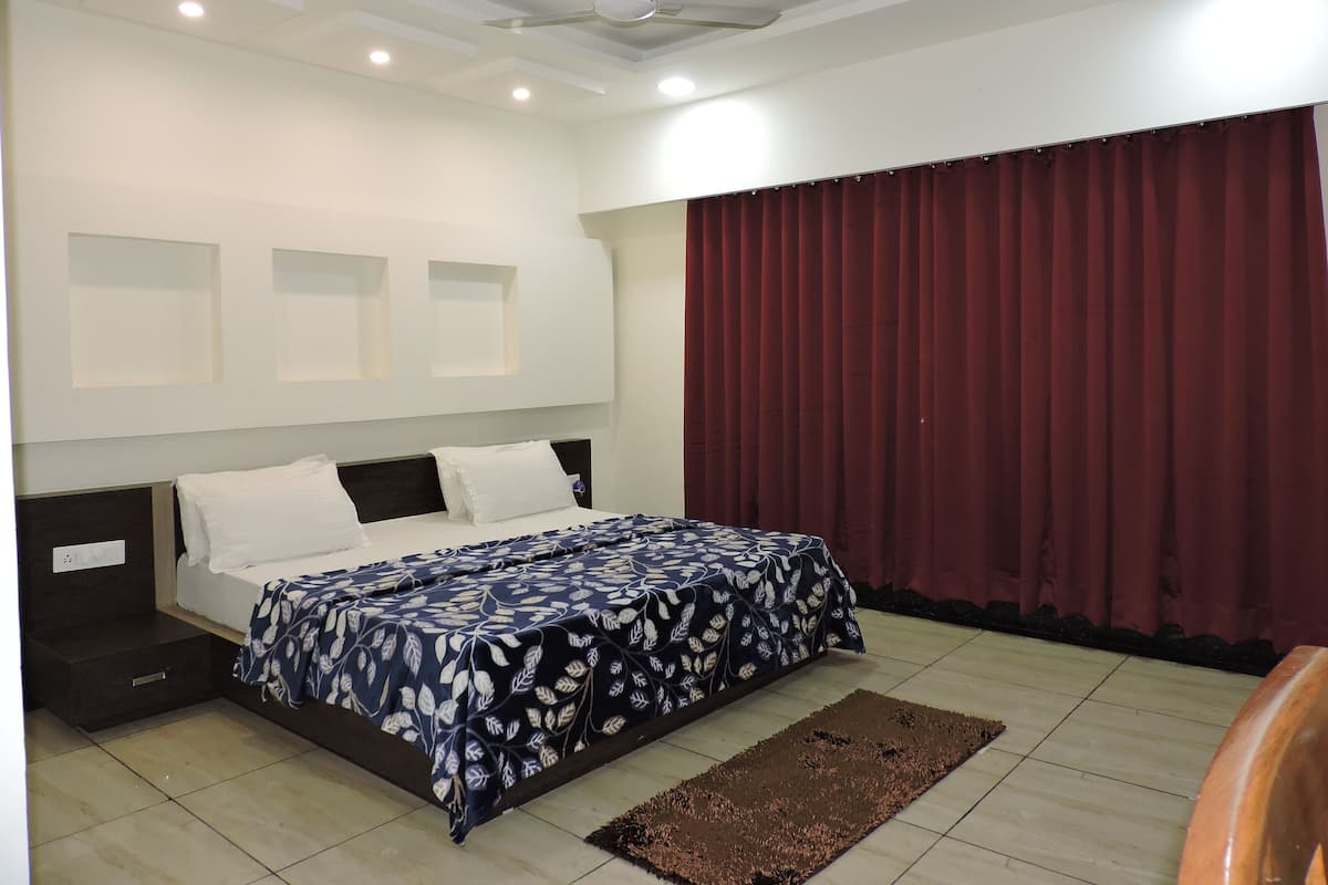 Un dormitorio con cama, ventilador de techo, iluminación empotrada, ventana con cortinas y suelo de baldosas.