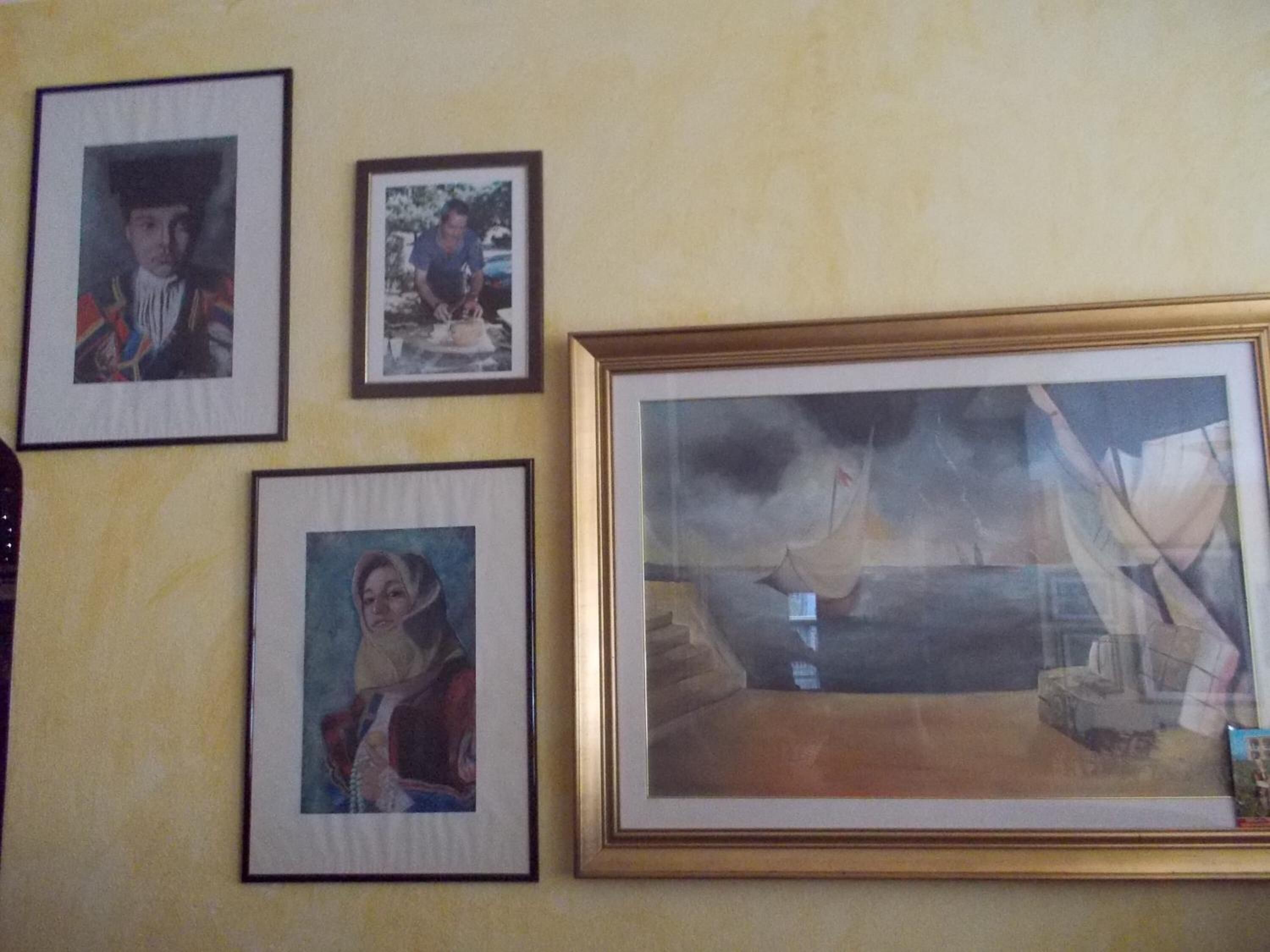 A wall with four framed pictures, including a large landscape painting.