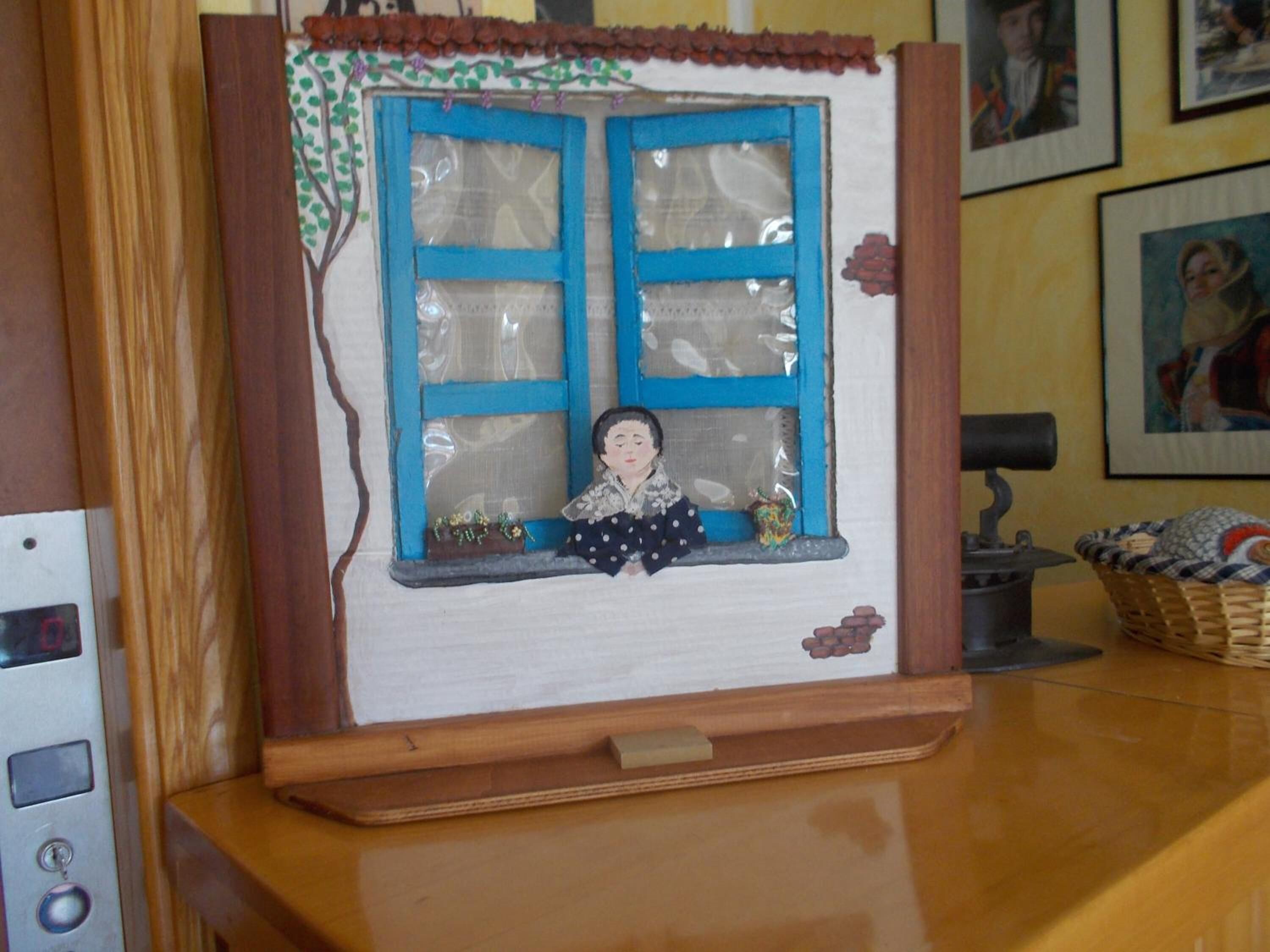 A wooden cabinet with a window display featuring a miniature scene with a figure and decorative elements.