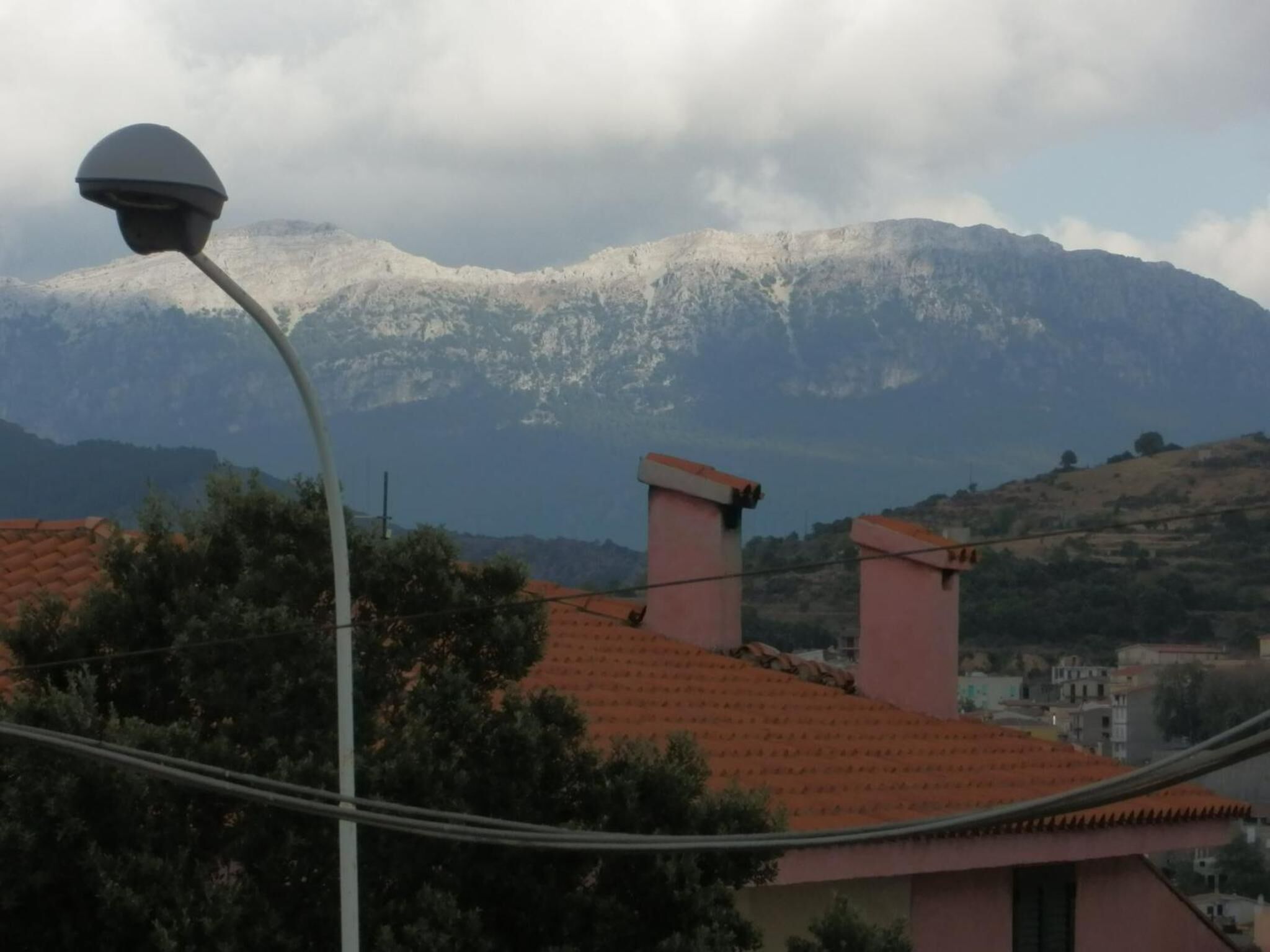 A building with a red-tiled roof and a street lamp in the foreground.