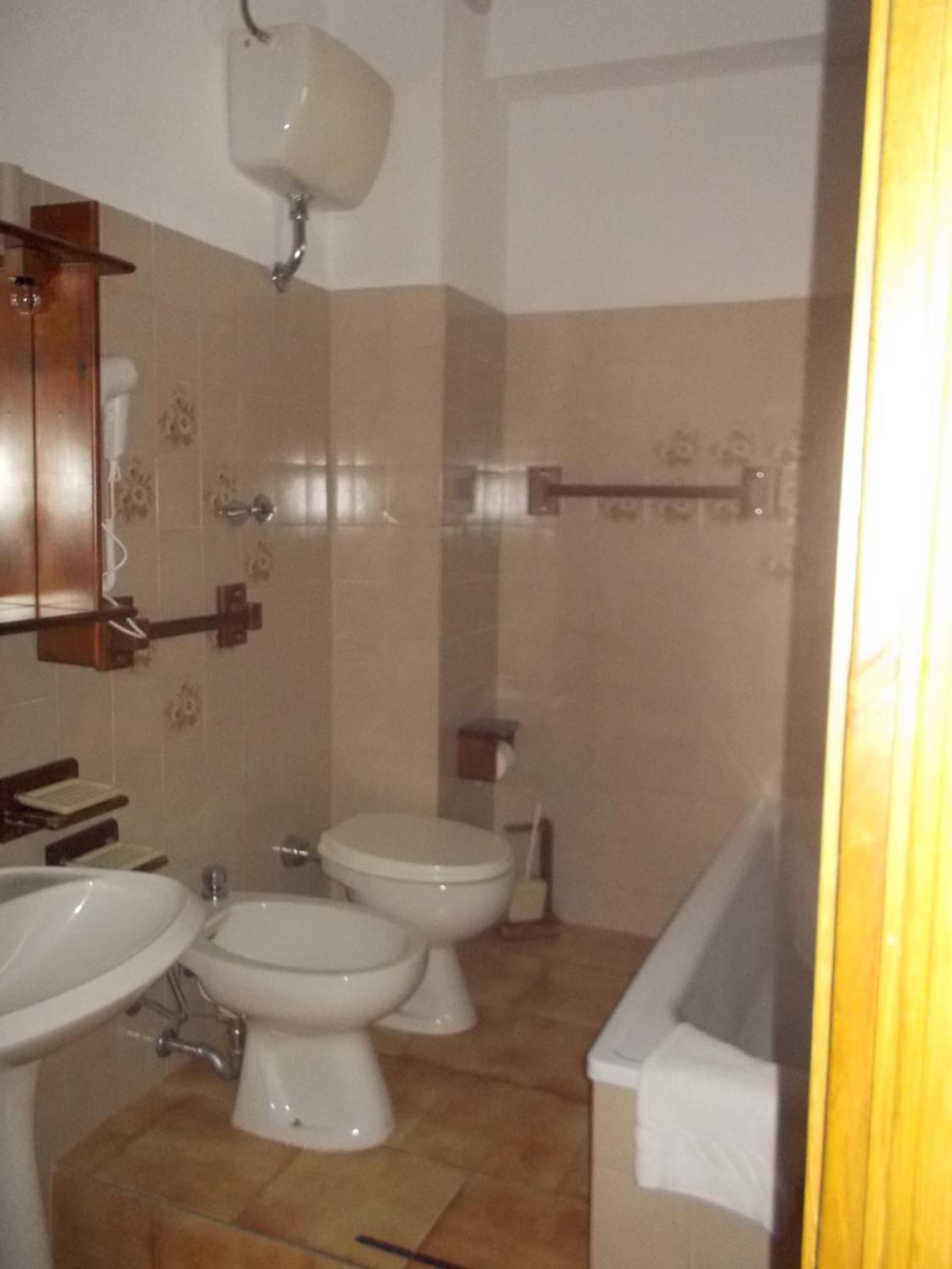 A bathroom with two toilets, a sink, and a shower area.