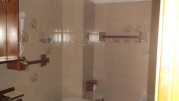 A bathroom with two toilets, a sink, and a shower area.