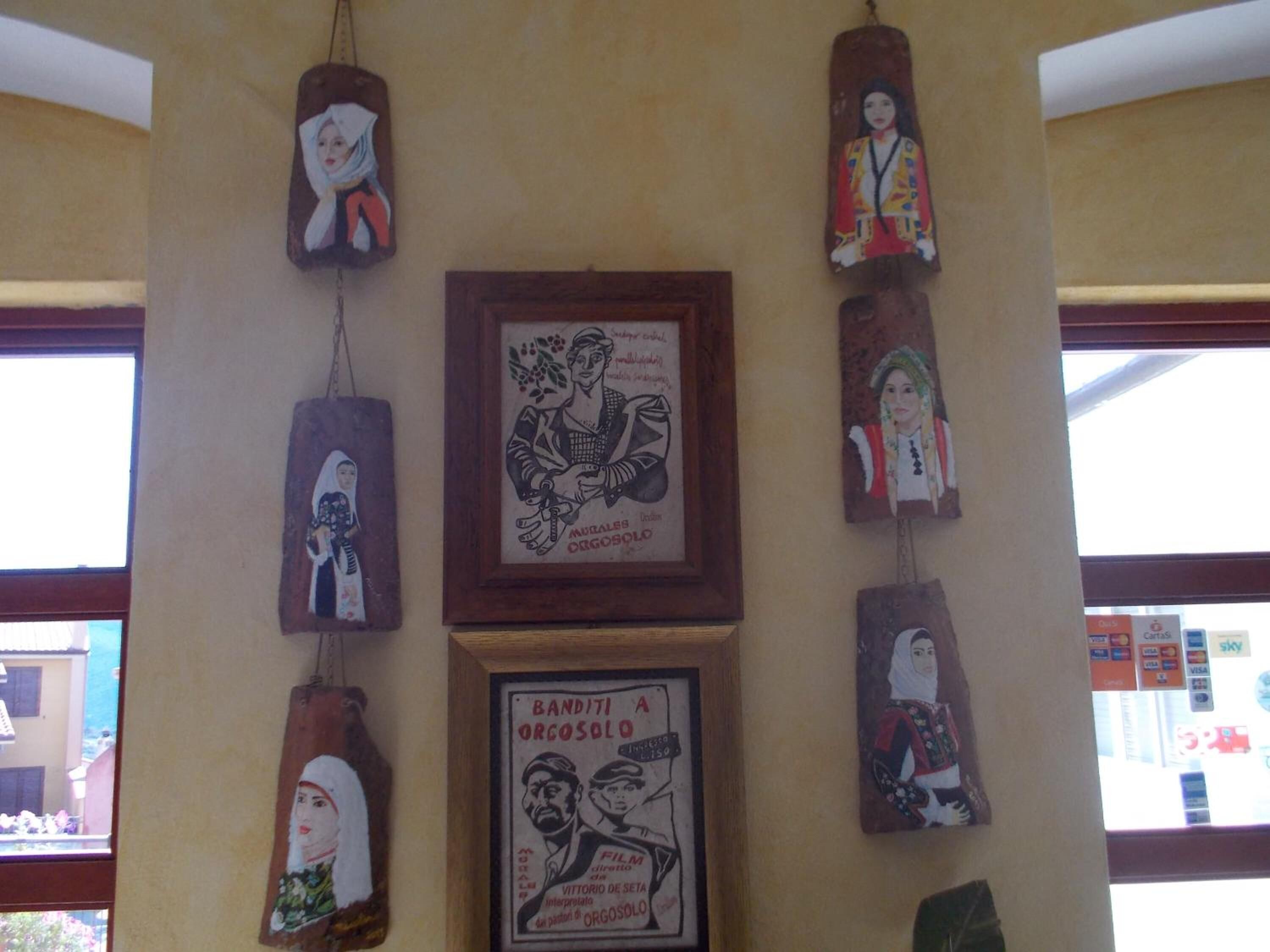 A wall with various framed artworks and posters, including a film poster for 'Banditi a Orgosolo'.