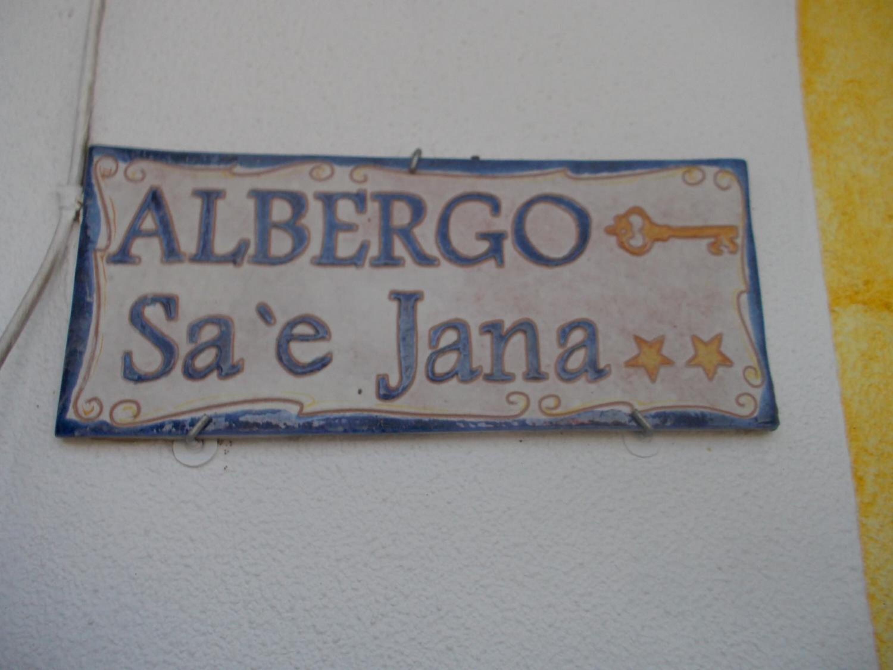 A sign with the name "ALBERGO Sa'e Jana" on a wall.