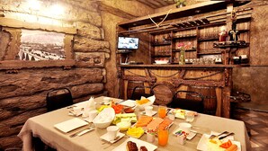 A dining area with a table set for breakfast, including plates of food, drinks, and a television mounted on the wall. - Marsel Hotel (Tbilisi)