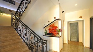 A staircase with ornate metal railings, a small shelf with flowers, and a door marked with the number 12. - Marsel Hotel (Tbilisi)