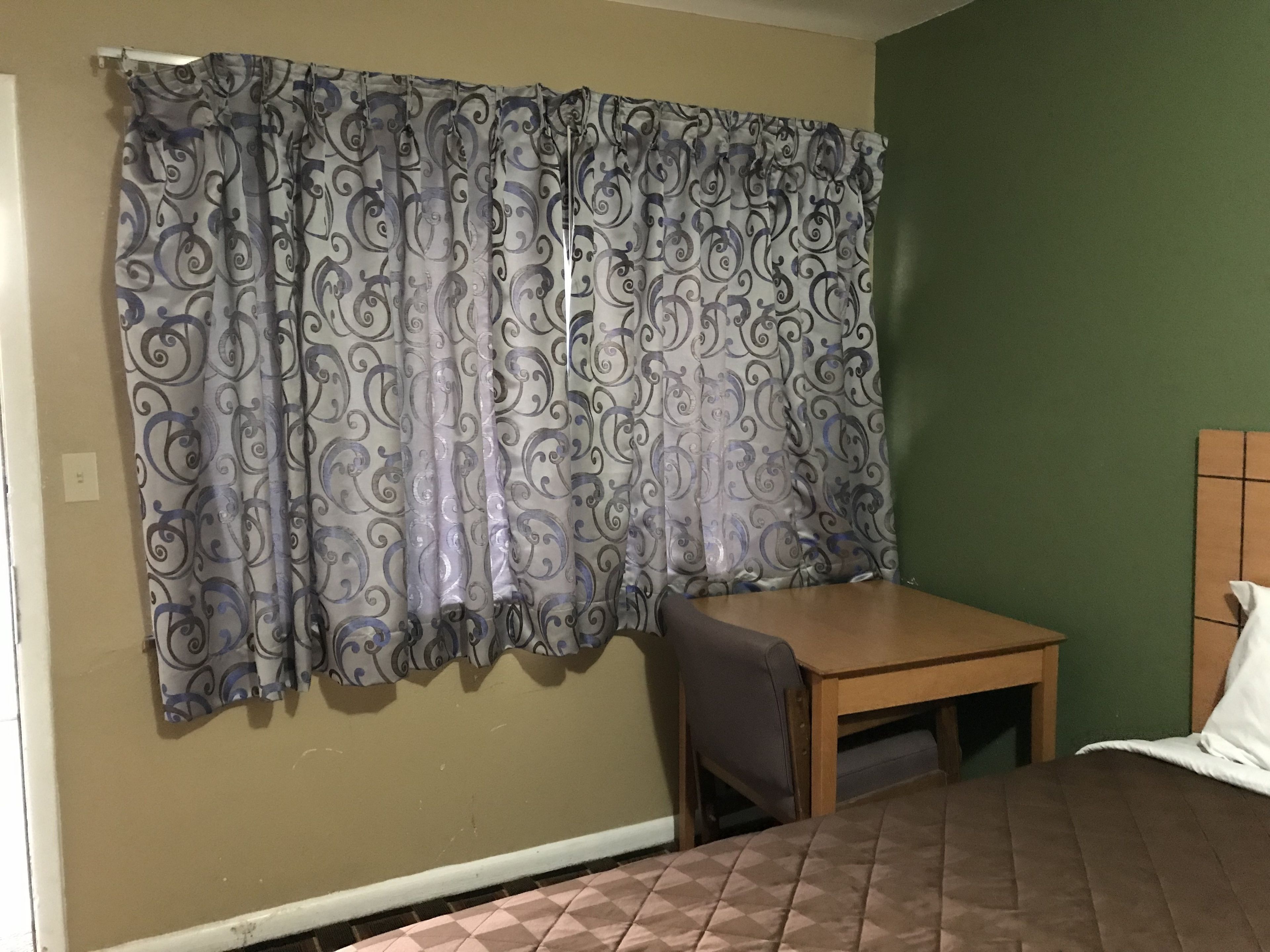 A room with a bed, a small table, and a chair.