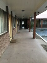 Un pasaje cubierto con paredes de ladrillo y ventanas, que conduce a la entrada de un edificio.