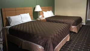 Habitación de hotel con dos camas, cada una con cubrecama marrón, almohadas blancas y una mesita de noche con lámpara y teléfono.
