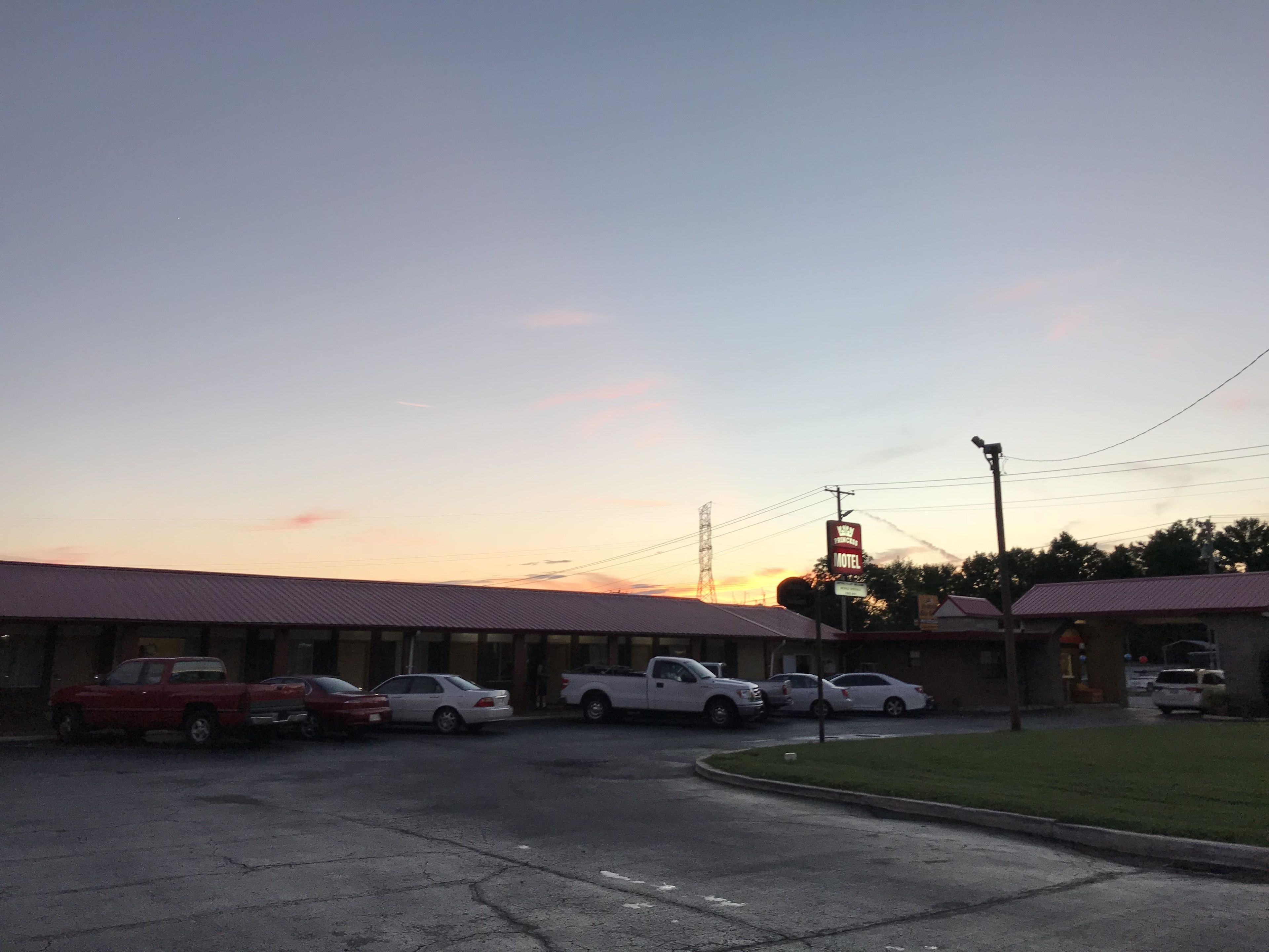 A motel with a red roof and a signboard. There are several cars parked in front.