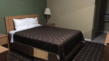 Un lit bien fait, avec une couverture à carreaux, une lampe de chevet et une table de nuit.