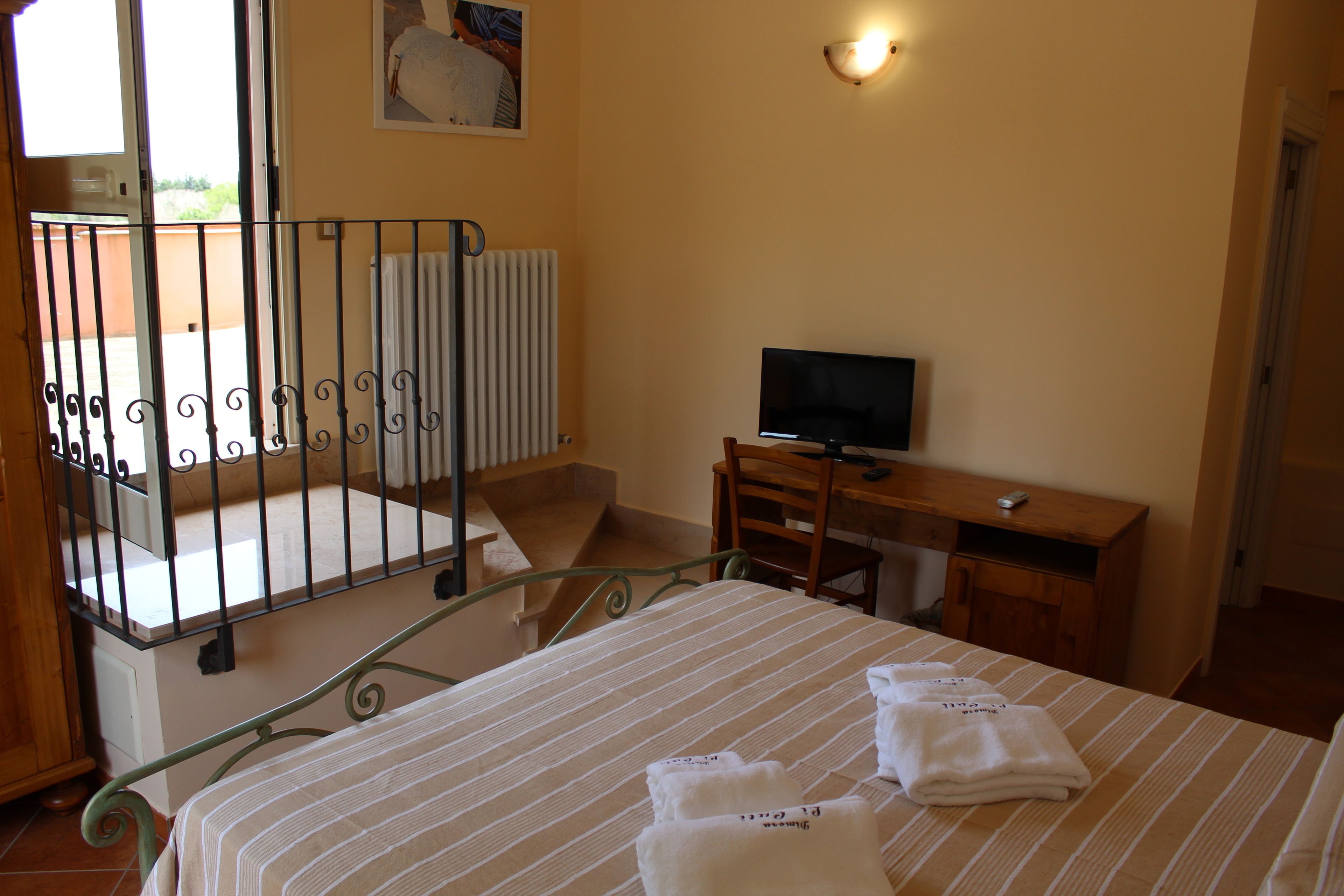 A hotel room with a bed, a desk with a television, a chair, and a radiator.