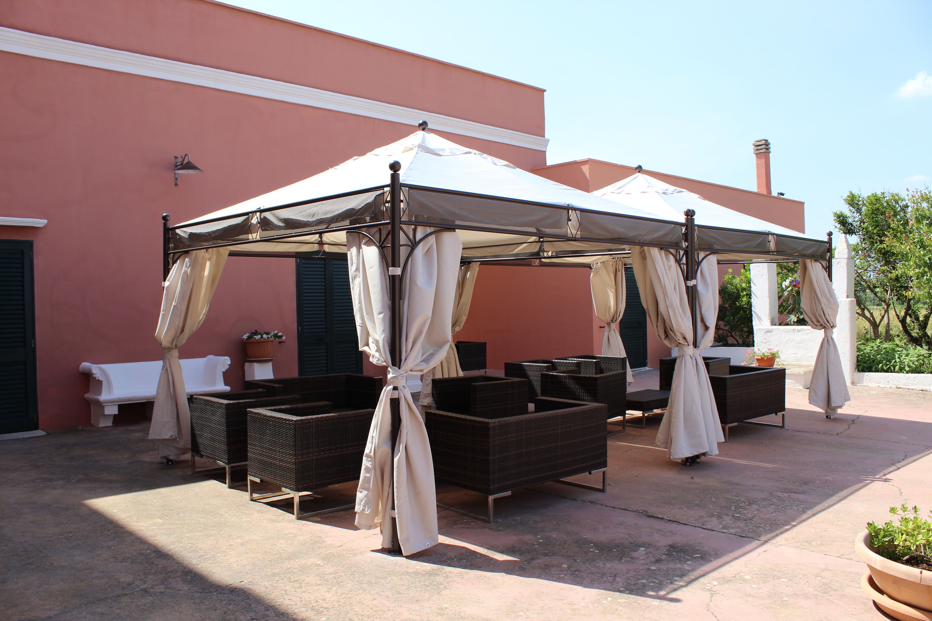A covered outdoor seating area with wicker furniture and a white canopy.