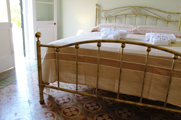 Una cama con estructura metálica y colcha a rayas.
