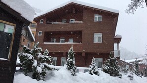Un edificio de varios pisos con fachada de ladrillo, balcones y alrededores cubiertos de nieve.