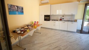 Una cuina moderna amb armaris blancs, una taula de fusta amb diversos objectes i un quadre a la paret.