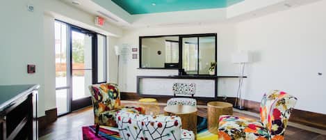 A lobby with a teal ceiling, a fire alarm, a reception desk, and colorful patterned chairs.