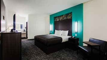 A hotel room with a large bed, a desk, a chair, and a TV.
