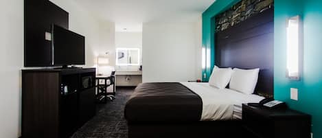 A hotel room with a bed, a desk, a television, and a nightstand.