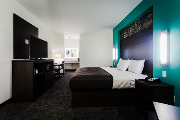 A hotel room with a bed, a desk, a television, and a nightstand. - Palacio Royale Inn Boutique Katy (Katy)