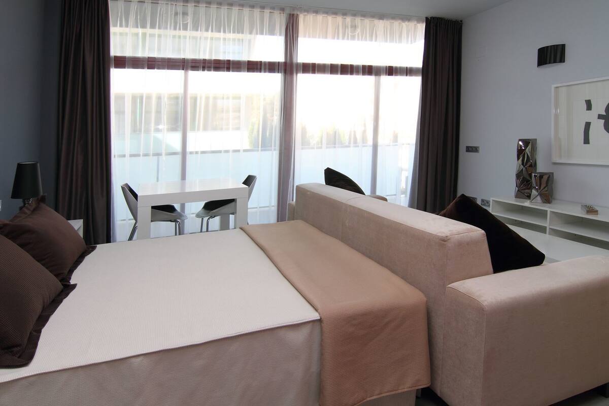 A hotel room with a bed, a sofa, a table, and a chair.