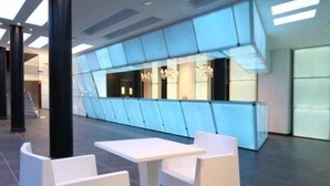 A modern lobby with a glass partition, white furniture, and a chandelier. - Aparthotel Four Elements Suites (Salou)