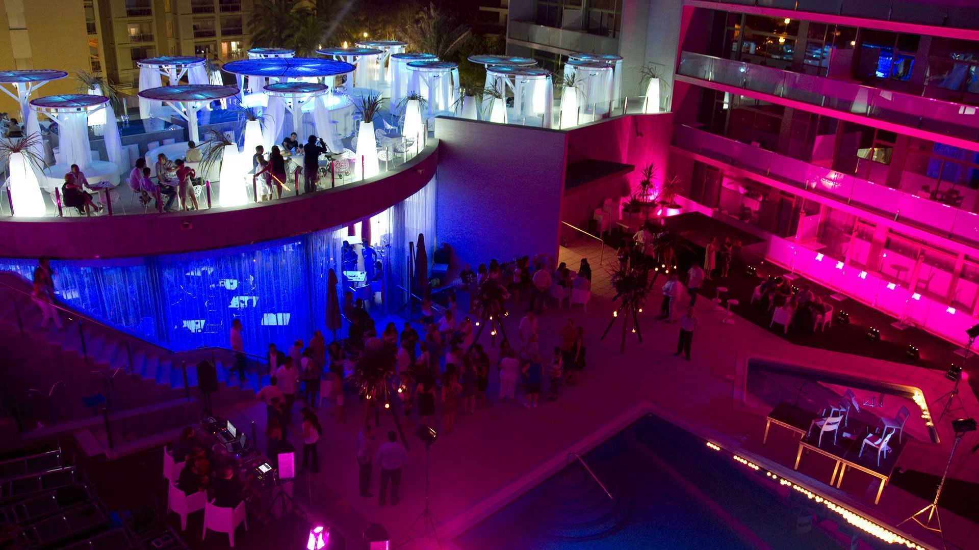 A multi-level indoor venue with a pool area, seating arrangements, and a stage for performances.