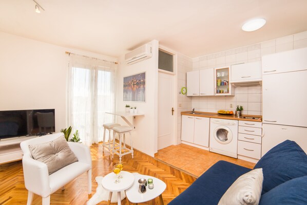 Een moderne woonkamer met een bank, een televisie en een eethoek.