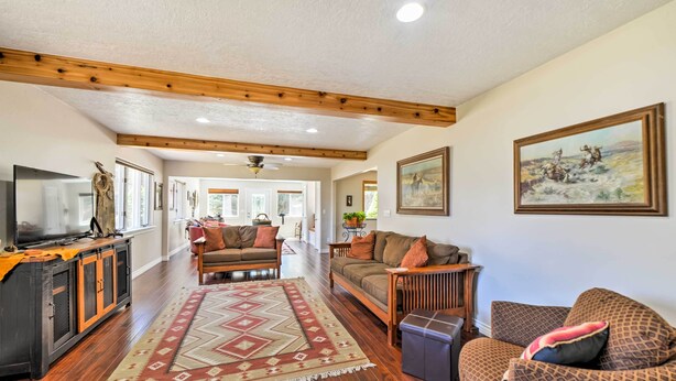 A spacious living room with hardwood floors, a large rug, and multiple seating areas.