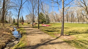 A park with a dirt path, a small stream, and hammock chairs.
