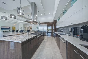 A modern kitchen with a large island, stainless steel appliances, and pendant lighting.