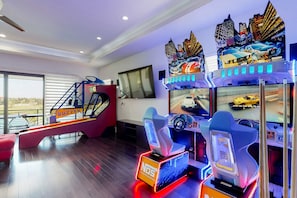 A room with a large window, a slide, and two racing game machines.