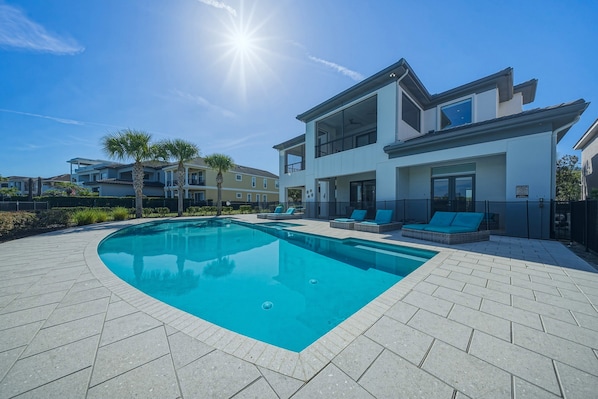 A modern two-story house with a swimming pool and outdoor seating.