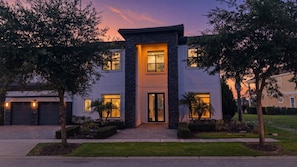 A modern two-story house with a stone facade, large windows, and a well-maintained lawn.