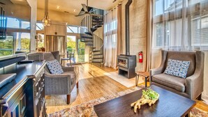 Amplia sala de estar con chimenea moderna, asientos cómodos y una escalera que lleva a un nivel superior.