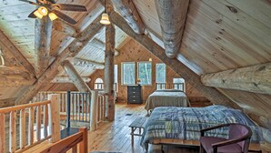 Una camera da letto mansardata accogliente, con travi in legno, due letti, una scrivania e una sedia.