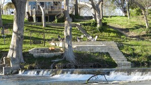 A house with a deck, a stone staircase, and a small waterfall.