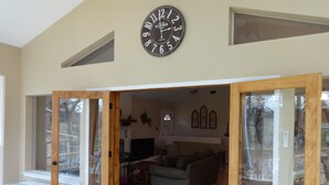 A spacious living room with a large clock on the wall, a sofa, and a television.