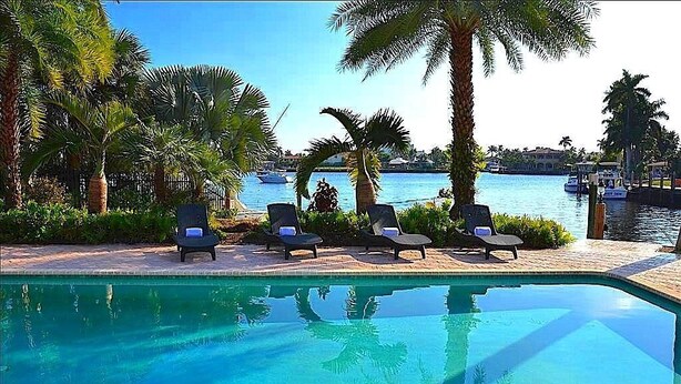 A pool area with lounge chairs and palm trees. - BY THE SEA VACATION VILLAS 5 BED WATERFRONT/ POOL LARGE ESTATE NEAR BEACH (Pompano Beach,)