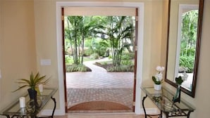 A hallway with glass tables, a white door leading to a paved outdoor area with palm trees. - BY THE SEA VACATION VILLAS 5 BED WATERFRONT/ POOL LARGE ESTATE NEAR BEACH (Pompano Beach,)