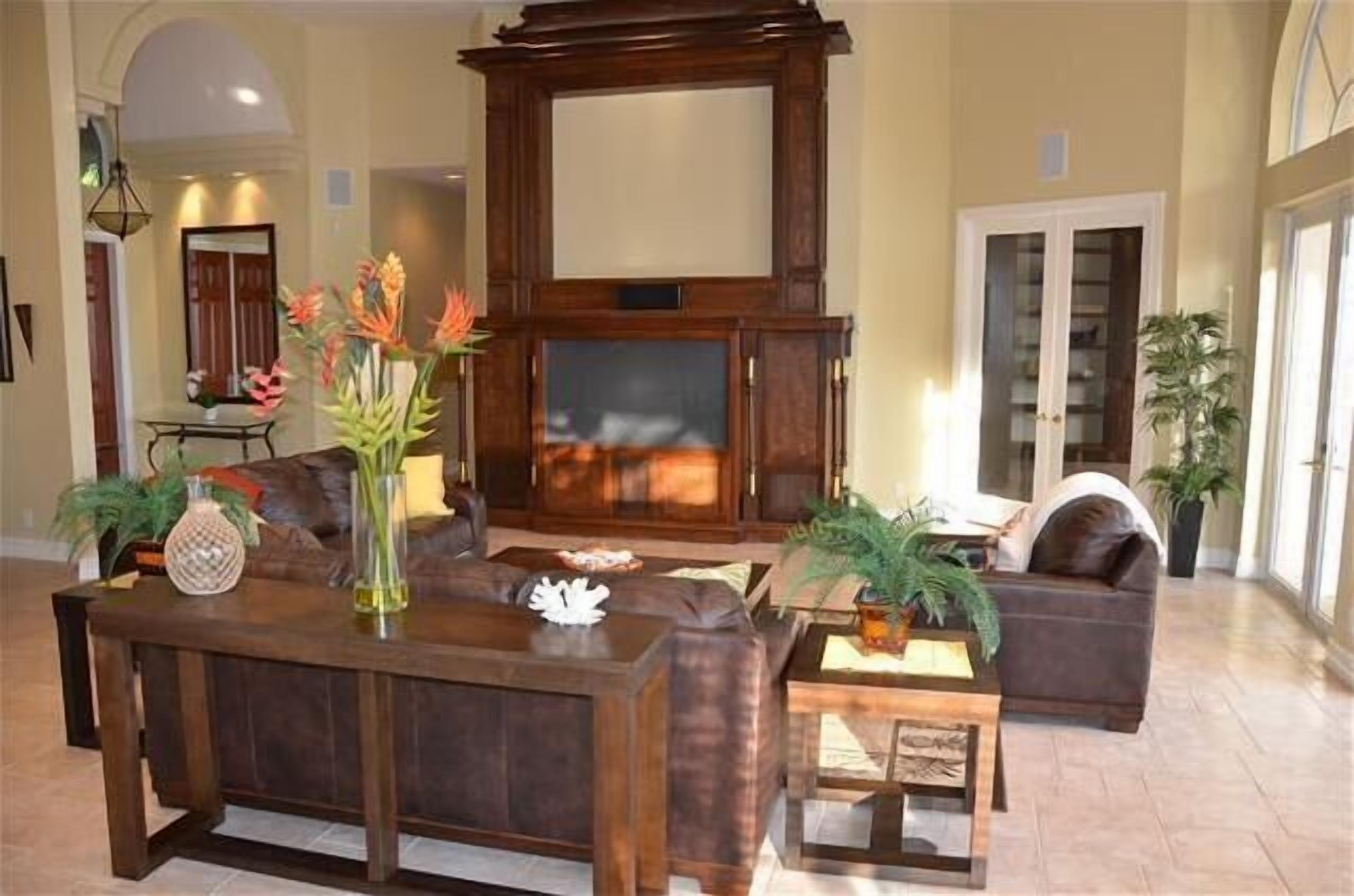 Un ampio soggiorno con un grande mobile in legno multifunzionale, divani in pelle e diverse piante decorative.